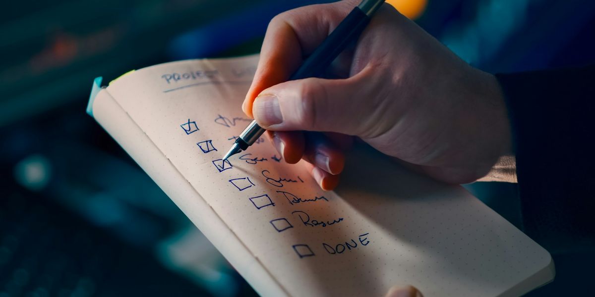 手書きのチェックリストに、ペンでチェックを入れている手元