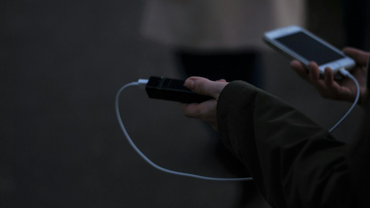 モバイルバッテリーとスマートフォンをケーブルでつないでいる手元